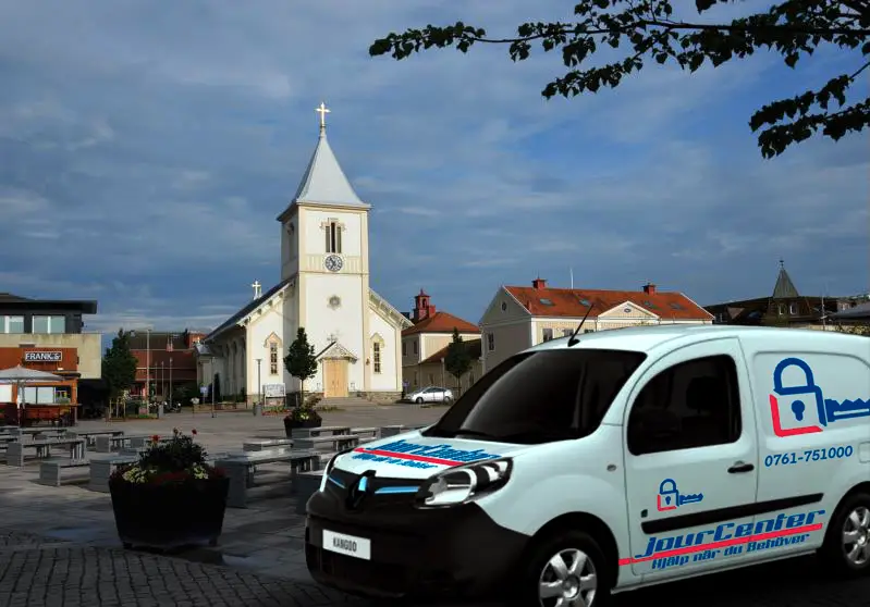 Vit skåpbil från Jourcenter som låssmed i Kungsbacka på öppet torg med kyrka i bakgrunden
